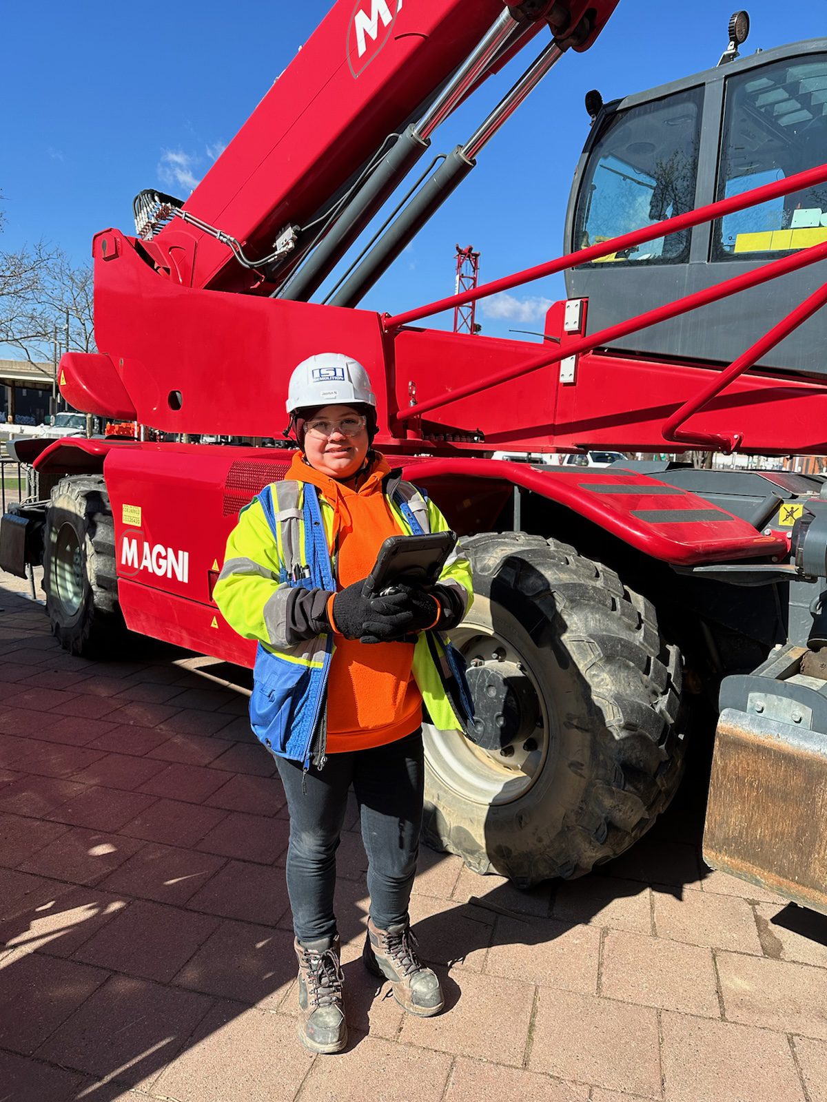 Female construction worker outside standing in front of red equipment